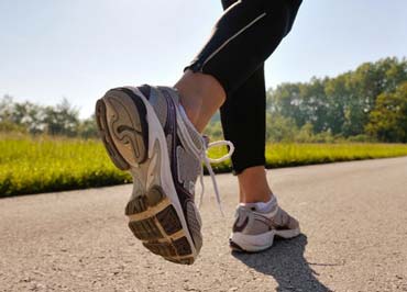 Primo piano di piedi che corrono e che suggeriscono l’esercizio fisico come buona regola di vita